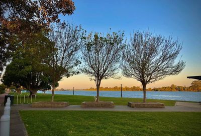 Park by lake against sky during sunset