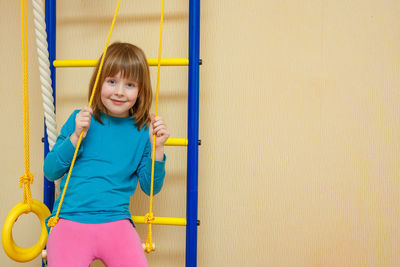 Portrait of smiling girl standing against wall