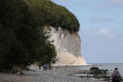 People standing against rock formation at beach