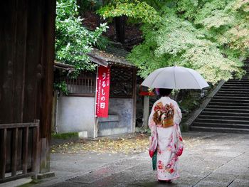 Rear view of woman with dog on footpath in rainy season