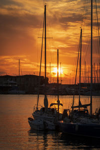 Boats moored at harbor during sunset