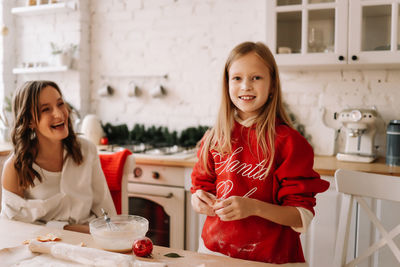 Mom and teenage daughter are preparing for the christmas holiday in the kitchen of the indoor house