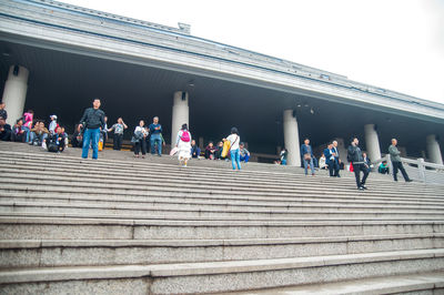 People on staircase in city against clear sky