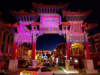 Low angle view of illuminated ornate gate over street at night
