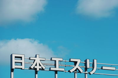 Low angle view of sign against blue sky