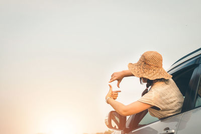 Woman sitting in car against clear sky