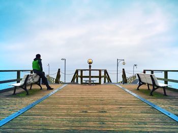 Rear view of man on pier over sea against sky