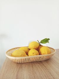 Close-up of oranges in basket on table against white background