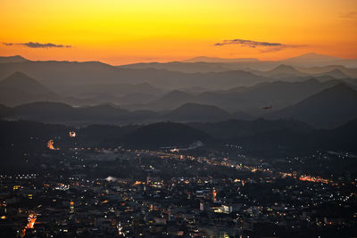 Aerial view of illuminated city against sky during sunset