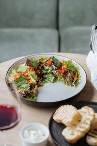 Top view of tasty salad with boiled octopus dried tomatoes elegant decorated with greenery on half plate and served with roasted bread