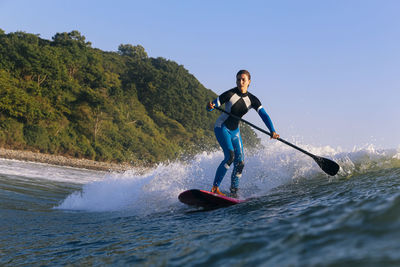 Female sup surfer at sunset time