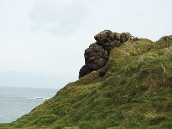 Scenic view of rocks by sea against sky