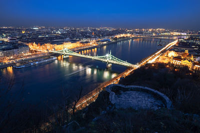 Illuminated bridge over river in city at night