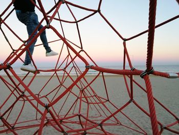 Metallic structure on beach against clear sky at sunset
