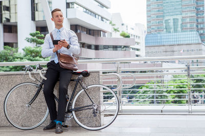 Man with bicycle against building in city