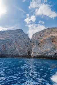 Scenic view of sea by mountain against sky