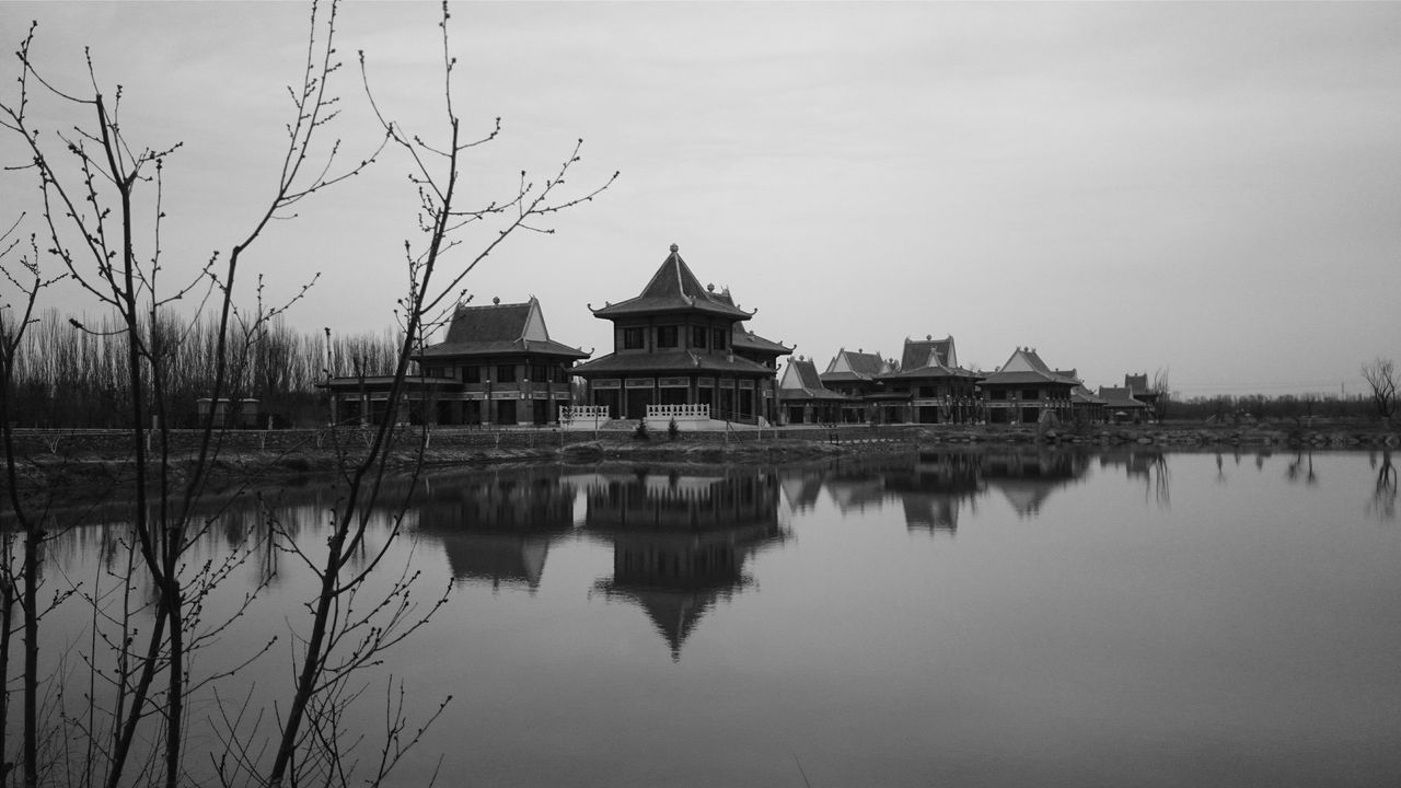 architecture, built structure, water, reflection, building exterior, waterfront, clear sky, lake, standing water, copy space, river, sky, history, tranquility, mid distance, outdoors, day, travel destinations, nature, tree