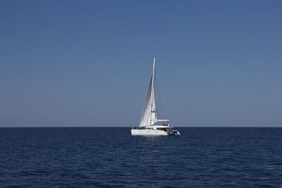 Sailboat sailing on sea against clear sky