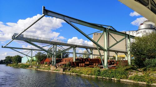 View of industrial equipment over river against sky