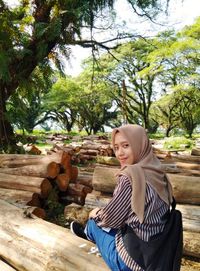 Portrait of smiling young woman sitting on wooden bench