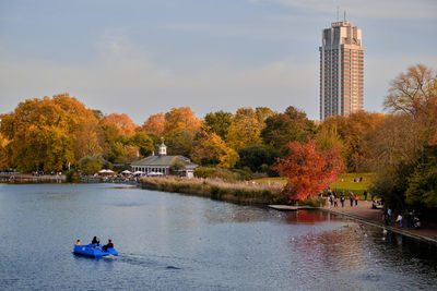 Rear view of people on boat on river against sky during sunset