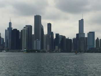 Sea by modern buildings against sky in city