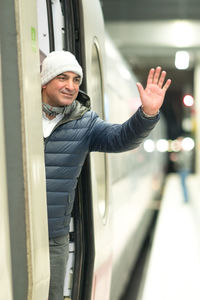 Man waving hand while standing in train