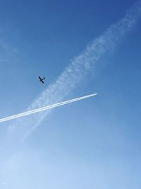 Low angle view of vapor trail against blue sky