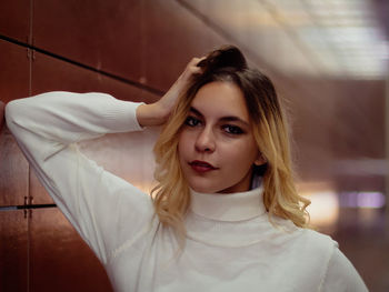 Portrait of beautiful young woman by wall