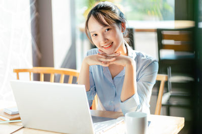 Portrait of young woman using laptop at table