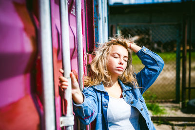 Beautiful young woman standing against wall