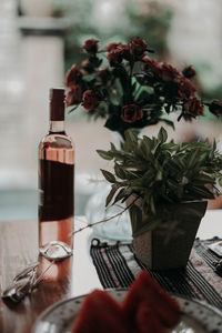 Bouquet with roses and a bottle of rose wine on a wooden table