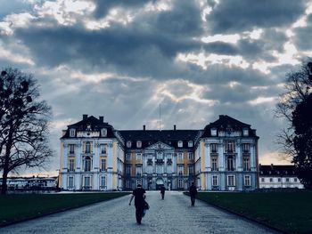 People walking by buildings against sky in city