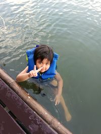 High angle portrait of boy showing peace sign while swimming in lake