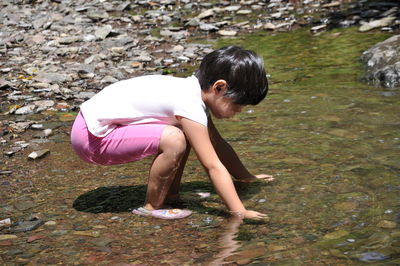 Side view of girl touching water