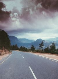 Road by trees against sky