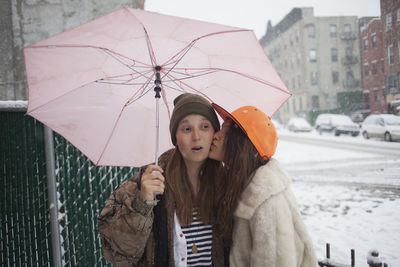 Portrait of woman with umbrella standing in winter