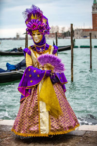 Woman wearing costume and mask against sea during venice carnival