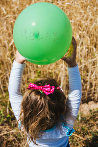 Rear view of girl holding balloon with relax text at field