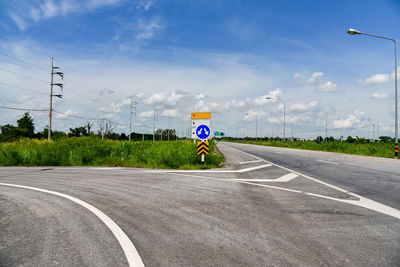 Road sign by street against sky