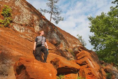 Low angle view of man on rock looking away against sky