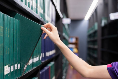 Close-up of hand removing book from shelf in library