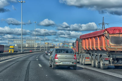 Vehicles on road in city against sky