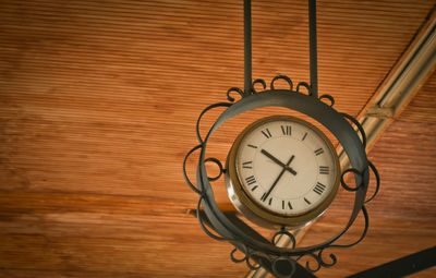 Close-up low angle view of clock hanging from ceiling