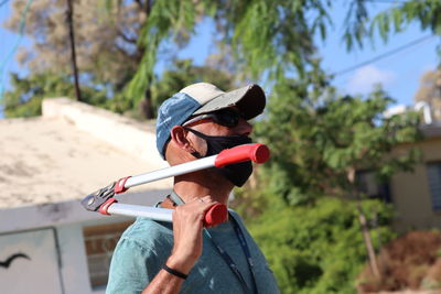 Midsection of man holding sunglasses against trees