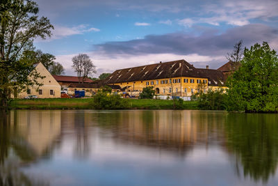 Houses by lake and buildings against sky