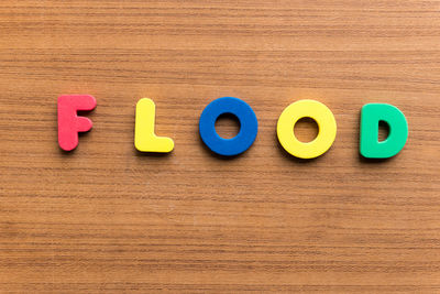 High angle view of colorful flood text on wooden table