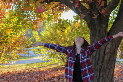 Young woman standing by tree in forest