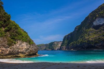 Scenic view of sea and mountains against blue sky