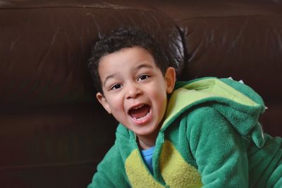 Portrait of boy shouting while sitting on sofa